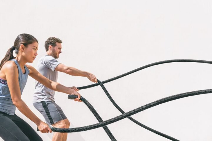 A man and woman exercising with battle ropes outside