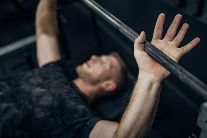 Man on a weight bench lying under a barbell in a gym