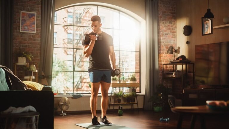 Man performs biceps curl with dumbbells in living room