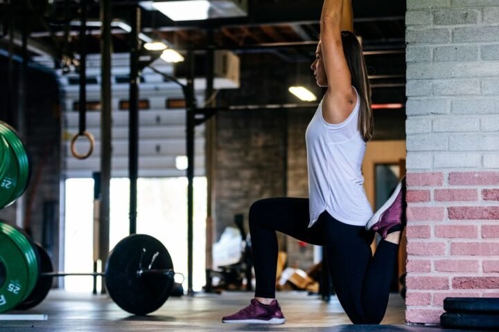 Woman performs couch stretch in gym