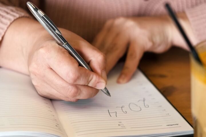 Close-up of hands writing in diary under