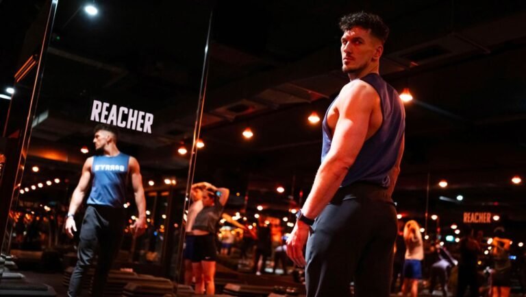 Barry&rsquo;s Bootcamp trainer facing floor-to-ceiling mirror. The word Reacher is printed on the mirror