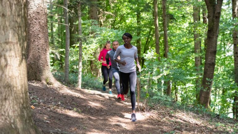 Group of three people running through a forest