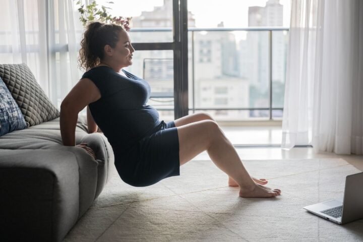 Woman uses couch to perform triceps dips at home