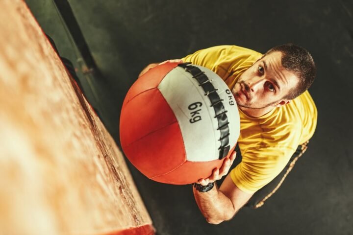 Man seen from above about to throw a large 6kg medicine ball up