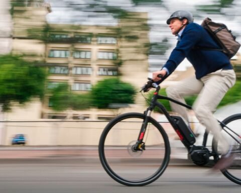 Man in casual business attire and bike helmet rides electric bike